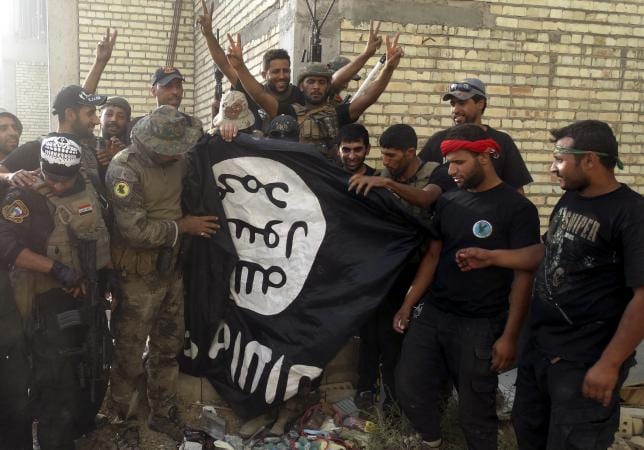 Iraqi security forces stand with an Islamist State flag which they pulled down at the University of Anbar, in Anbar province