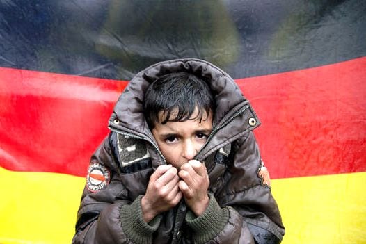 5012484_6_9f84_un-enfant-migrant-devant-un-drapeau-allemand_62bac179947d6e7679339ef45f1dd0f2