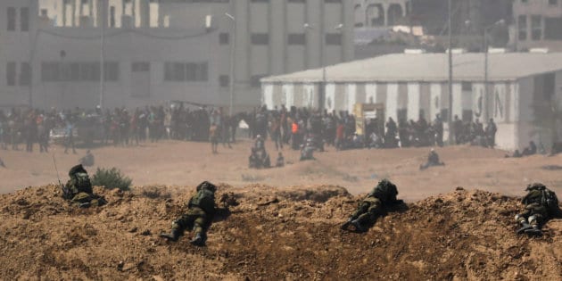 Smoke rises as Israeli soldiers are seen on the Israeli side of the border with the Gaza Strip
