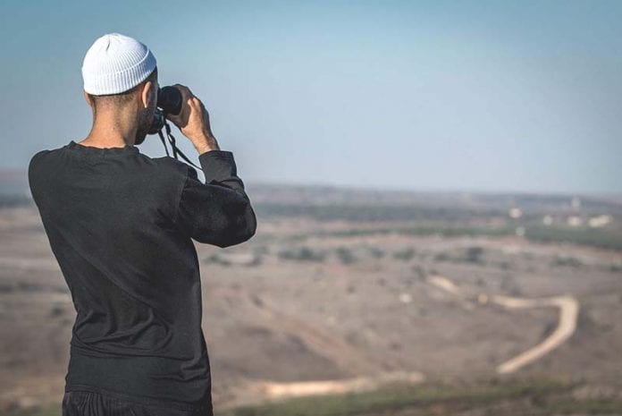A-Druze-man-watches-fighting-between-rebels-and-the-government-army-on-the-Syrian-Golan-696x465