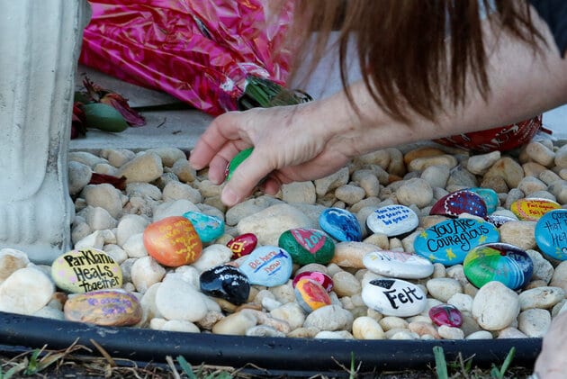 Suzanne Devine Clark places items on a memorial on the one year anniversary of the shooting which claimed 17 lives at Marjory Stoneman Douglas High School in Parkland