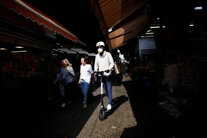 1300134-a-man-rides-a-scooter-while-wearing-mask-at-a-food-market-in-tel-aviv