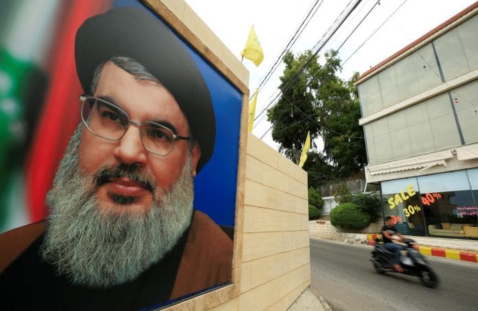 A man rides a motorbike past a picture of Lebanon's Hezbollah leader Sayyed Hassan Nasrallah, near Sidon