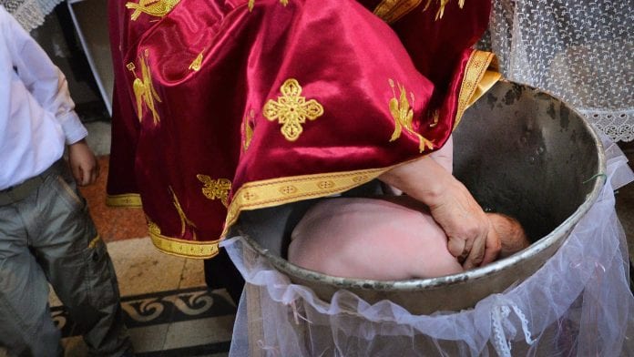 Un-pretre-orthodoxe-pratiquant-un-bapteme-en-Roumanie-en-2014-964141