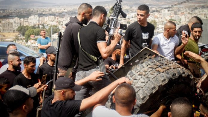 Palestinians_gather_around_parts_of_an_Israeli_vehicle