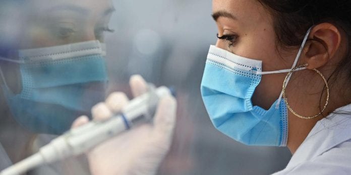 A laboratory technician uses a pipette device to process samples to t