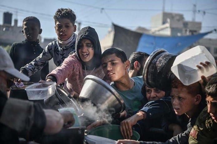 Gazans-converge-on-a-station-delivering-humanitarian-aid.-696x463