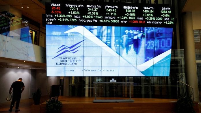 FILE PHOTO: A man walks past an electronic board displaying market data at the Tel Aviv Stock Exchange, in Tel Aviv, Israel