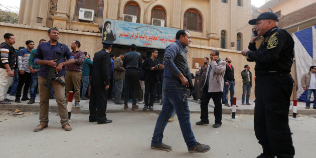 Security forces and people gather at the site of attack on a church in the Helwan district south of Cairo