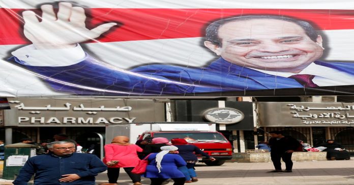 People walk by a poster of Egypt's President Abdel Fattah al-Sisi for the upcoming presidential election, in Cairo