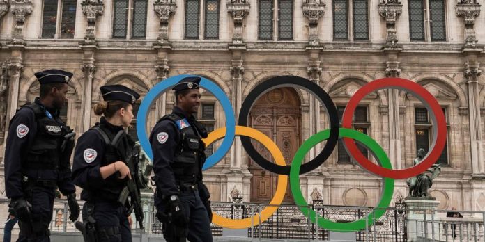 A woman walks past Paris' City Hall where the five-Olympic rings are