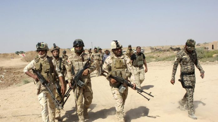 Iraqi security forces and Iraqi Shi'ite volunteers carry their weapons during an intensive security deployment to fight against militants of the Islamic State on the outskirt of Sulaiman Pek town
